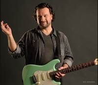 Paul standing with green guitar